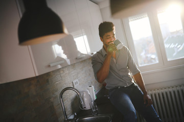 Naklejka na ściany i meble Handsome african american man drinking coffee in kitchen