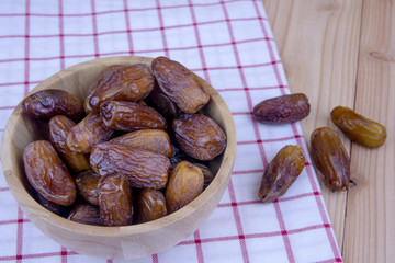 Close up of a plate of dried dates on a wooden background.