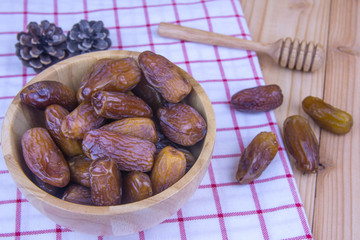 Close up of a plate of dried dates on a wooden background.