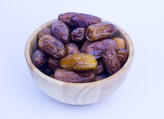 Close up of a plate of dried dates on a wooden background.