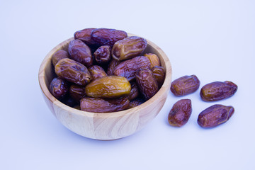 Close up of a plate of dried dates on a wooden background.