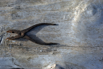 Old iron rusty pliers on Cracked old boards, grunge texture background