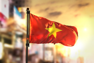 Vietnam Flag Against City Blurred Background At Sunrise Backlight