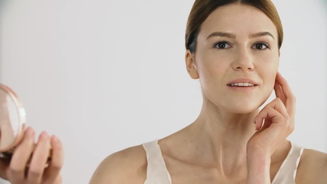 Facial Skin Care. Woman With Mirror Applying Skin Cosmetics