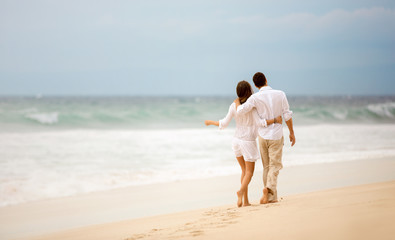 Fototapeta na wymiar Embracing couple walking along beach