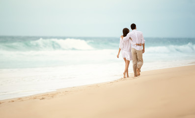 Fototapeta na wymiar Back view of a romantic couple walking at beach