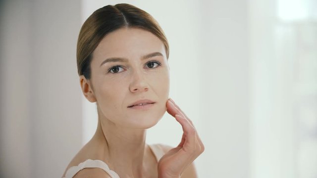 Cosmetology. Beautiful Mature Woman Massaging Facial Skin