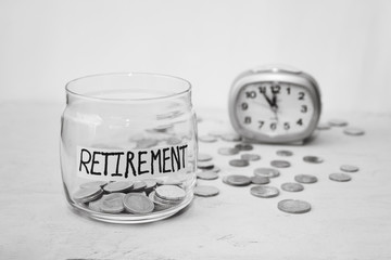 Close up Coins in glass jar with alarm clock for time to money saving for retirement concept , vintage color tone