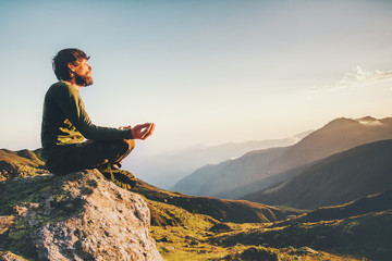 Man meditating yoga at mountains Travel Lifestyle relaxation emotional concept adventure summer vacations outdoor harmony with nature landscape - obrazy, fototapety, plakaty