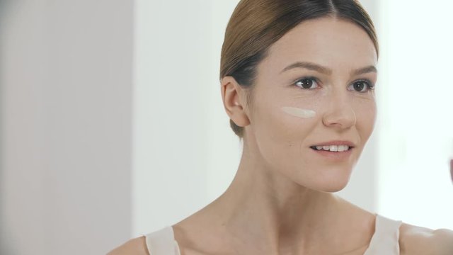 Beauty Face. Beautiful Woman Applying Liquid Foundation On Skin