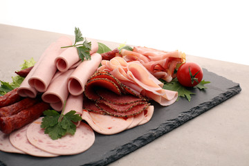 Food tray with delicious salami, pieces of sliced ham, sausage, tomatoes, salad and vegetable - Meat platter with selection