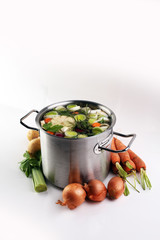 Broth with carrots, onions various fresh vegetables in a pot - c