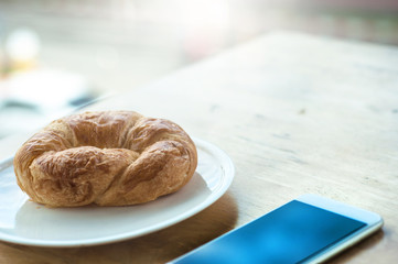 breakfast at offce with croissant and smart phone