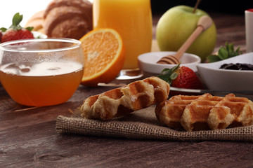 breakfast on table with waffles, croissants, coffe and juice