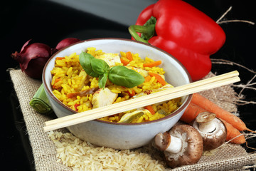 Homemade Chinese fried rice with vegetables, chicken and fried eggs served on a plate with chopsticks