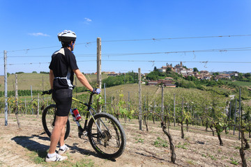 Man with mountain bike on vineyards, Langhe, Italy