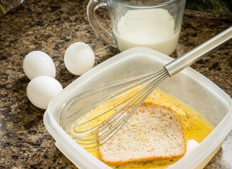 horizontal image of French toast being prepared with eggs and milk and a piece of whole wheat bread...