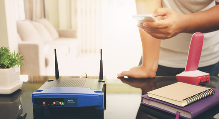 closeup of a wireless router and a young man using smart phone on living room at home
