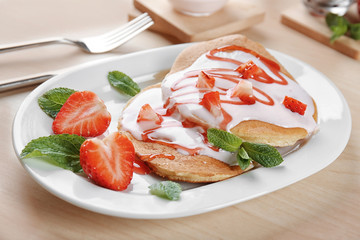 Delicious pancakes with strawberry and yogurt on plate