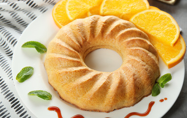 Plate with appetizing citrus cake and orange slices, close up