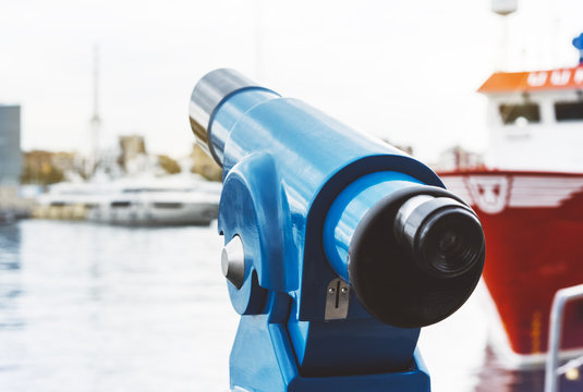 Touristic telescope look at city and sea with sunset view, blue binoculars on background viewpoint the pier port red ship yacht, coin operated in panorama observation sunrise nature, mock up