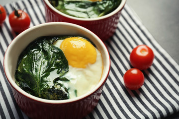 Portion of eggs Florentine with cherry tomatoes on striped napkin, closeup