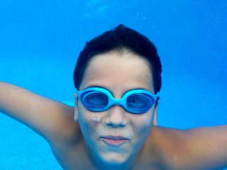 El chico esta nadando en la piscina con gafas de buseo