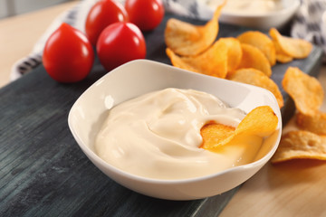 Bowl with tasty mayonnaise sauce and chips on table, closeup