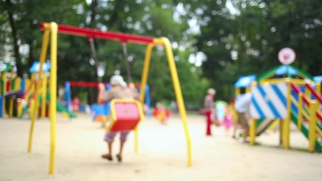 Kids have fun on children public playground outdoors on summer sunny day. Blurred real time full hd video footage.