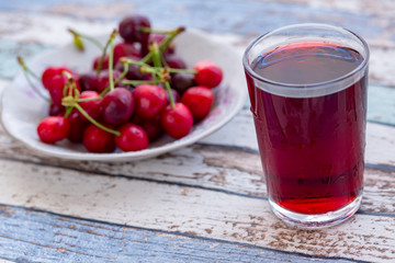 Cherry juice with cherries in plate on turquoise vintage table
