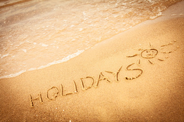 The word holidays written in the sand on a beach