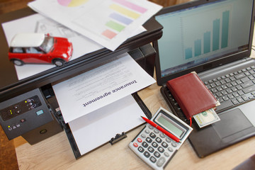 Homeowner and car Insurance form with Laptop, Printer, pen, dollars, calculator on the table