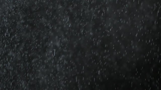 Rain or snow fall concept. Falling raindrops or snow against a black background. Close-up shot
