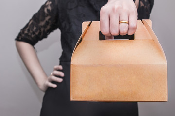 A woman in black dress stood with arms akimbo and bringing a snack box