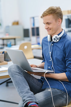 junger mann im büro mit laptop und kopfhörern