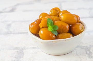 Raw fresh dates and green mint in a bowl on brick wall background close up. Selective focus.