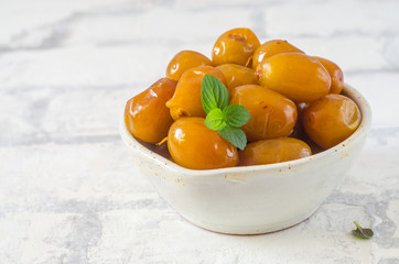 Raw fresh dates and green mint in a bowl on brick wall background close up. Selective focus.