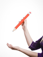 Female hand holds big red pencil