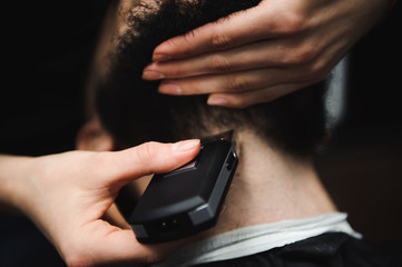 Master cuts hair and beard of men in the barbershop, hairdresser makes hairstyle for a young man