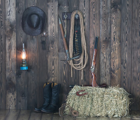 Fototapeta na wymiar Cowboy hat, boots and weapons on the background of the old barn.Wild west, cowboy,Vintage