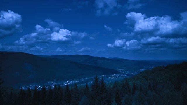 The dark picturesque mountains cloudy landscape with city in the valley at night