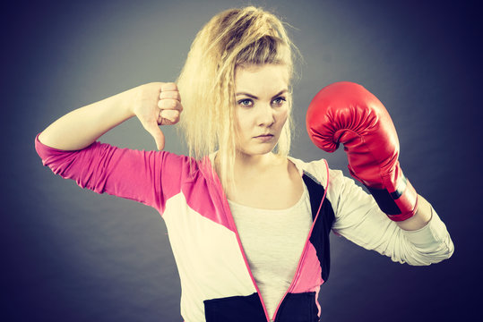 Woman wearing boxing gloves showing thumb down