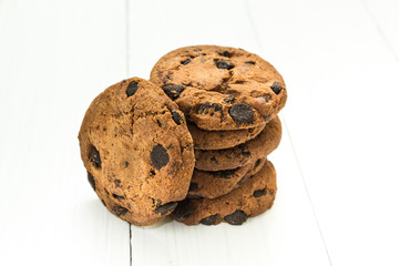 Chocolate homemade cookies on a white wooden table in the shape of a pile.