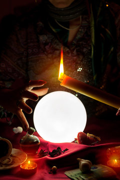 Crystal ball, candle and hand of gypsy fortune teller woman