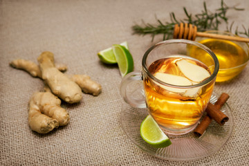 Glass of ginger tea with lime, raw ginger, cinnamon and honey