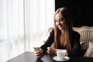 Portrait of young businesswoman use mobile phone while sitting in comfortable coffee shop during work break