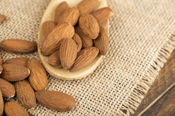 Close-up of almonds and wooden spoon on cloth. Food.