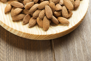 Close-up of almonds on wooden plate. Copy space.
