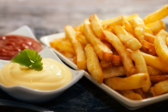Close up with french fries and small bowls with tomato sauce and mayonnaise