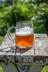 close up of a single glass of beer outside in the sunlight